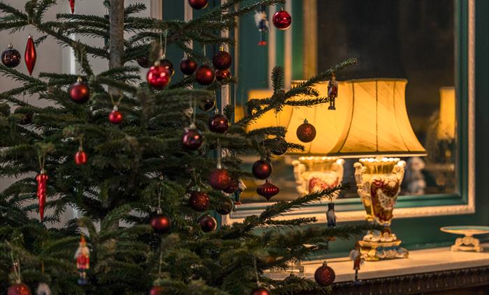 A traditional Christmas tree with red festive decorations.